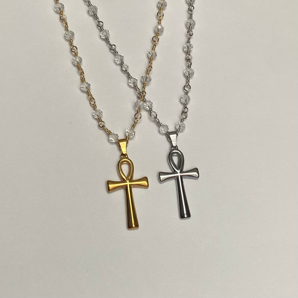 Two necklaces, one with a gold-colored and the other with a silver-colored Ankh pendant, both on a chain with transparent beads.