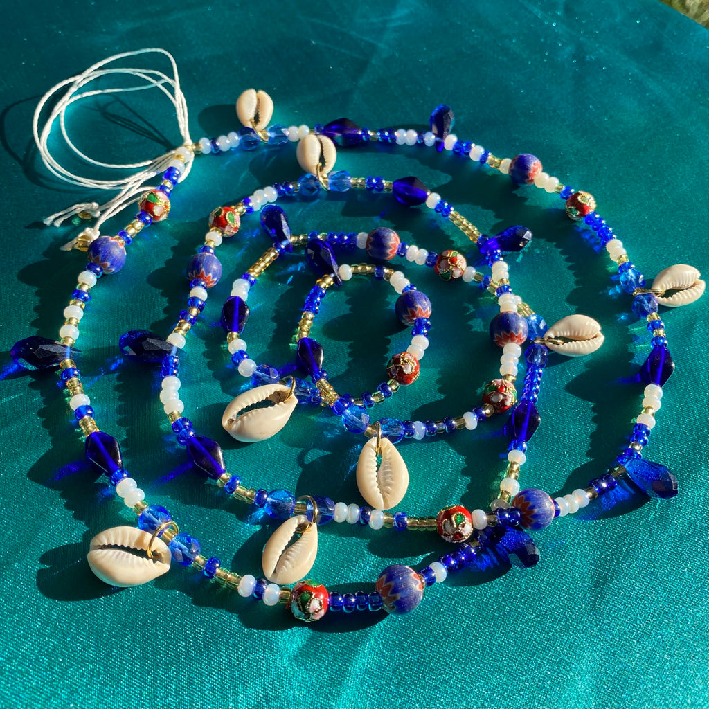 Blue, white and gold waist beads made with cowrie shells and a variety of blue, white and red beads.