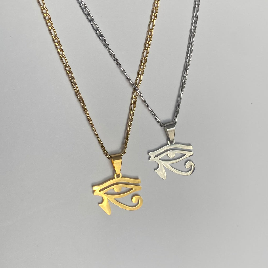 Two necklaces, one with a gold-colored chain and eye of ra pendant, and the other with a silver-colored chain and eye of ra pendant, displayed side by side against a light background.