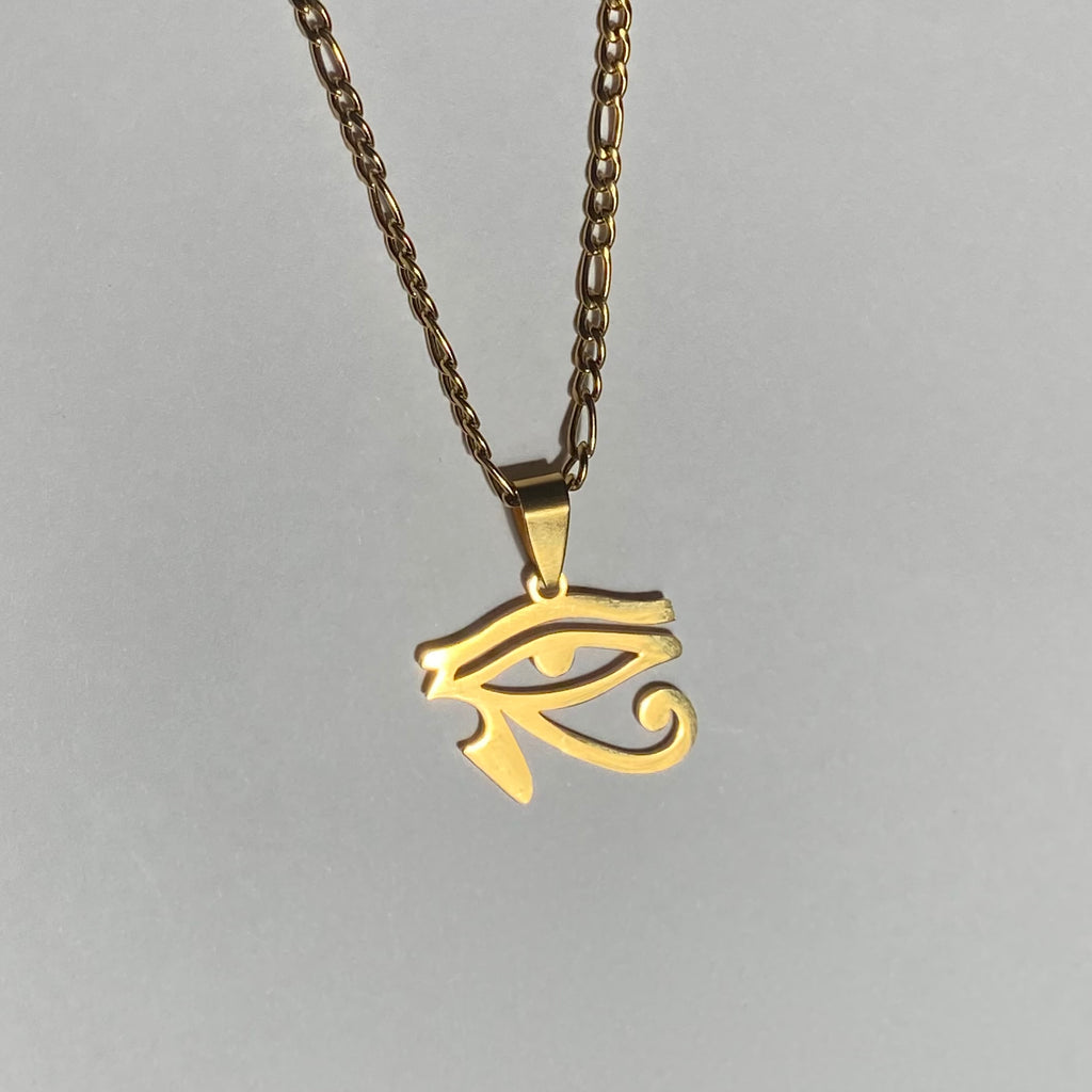 necklace with gold colored chain and eye of ra pendant, displayed on a light background.